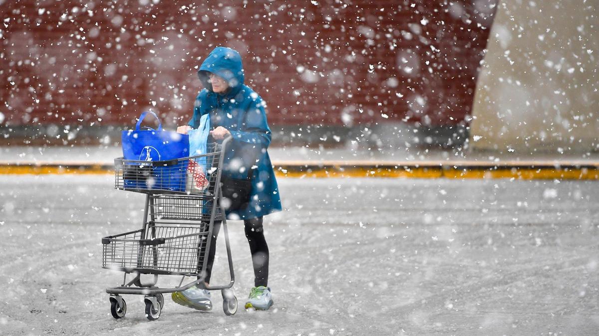 Snow fell as a shopper headed to the parking lot of a grocery store in Shawnee, Kansas, in January 2024.