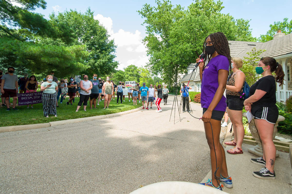 Tori Swanson speaks to protesters in front of the president’s residence at Kansas State University on Saturday.