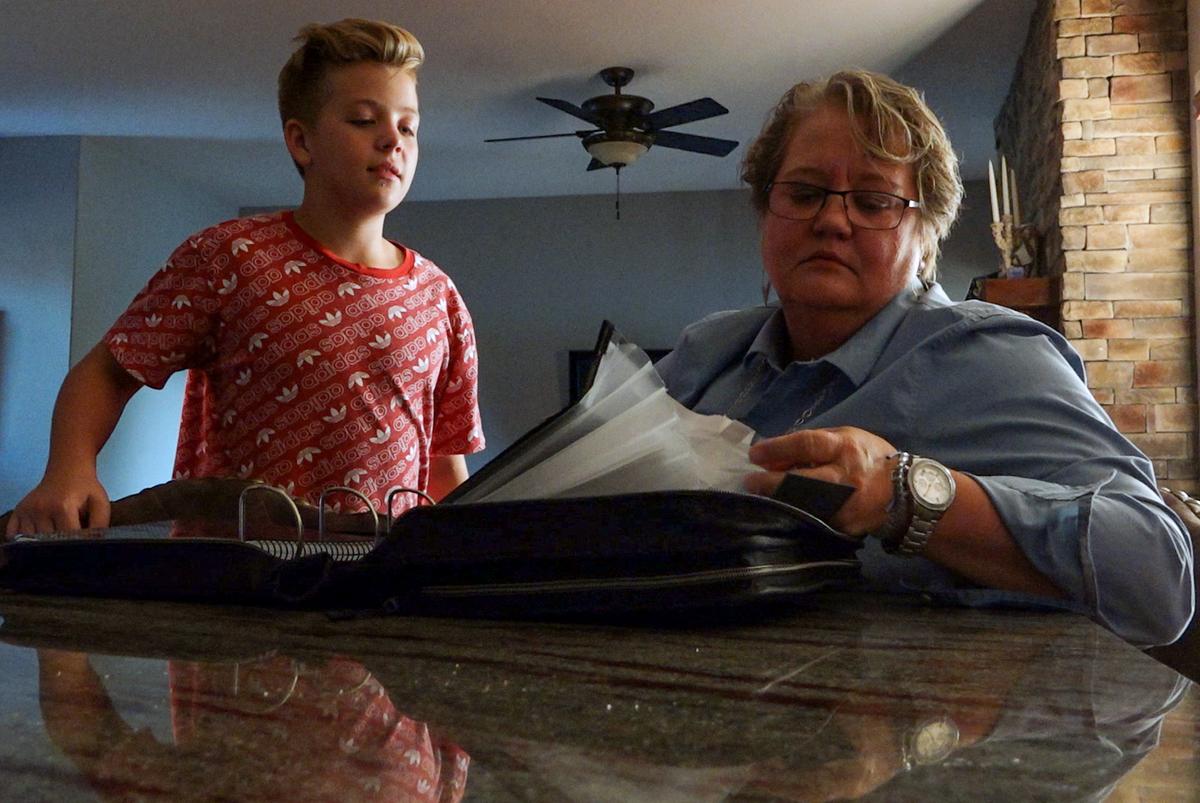Jak Guimbellot and one of his mothers, Kate Guimbellot, look over his school folder in their Olathe home. They’re both urging the city to pass a nondiscrimination ordinance.