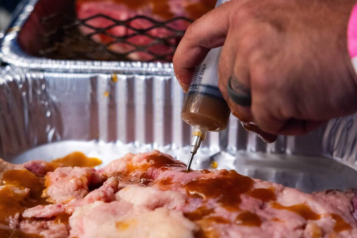 Chris Jackson, head cook of Open Flame BBQ, prepares their brisket for its long overnight cook by injecting the brisket with sauce and spices at The Great Lenexa BBQ Battle on Friday, June 26, 2026. “The weekend is like my guilty pleasure,” quoted Jackson.