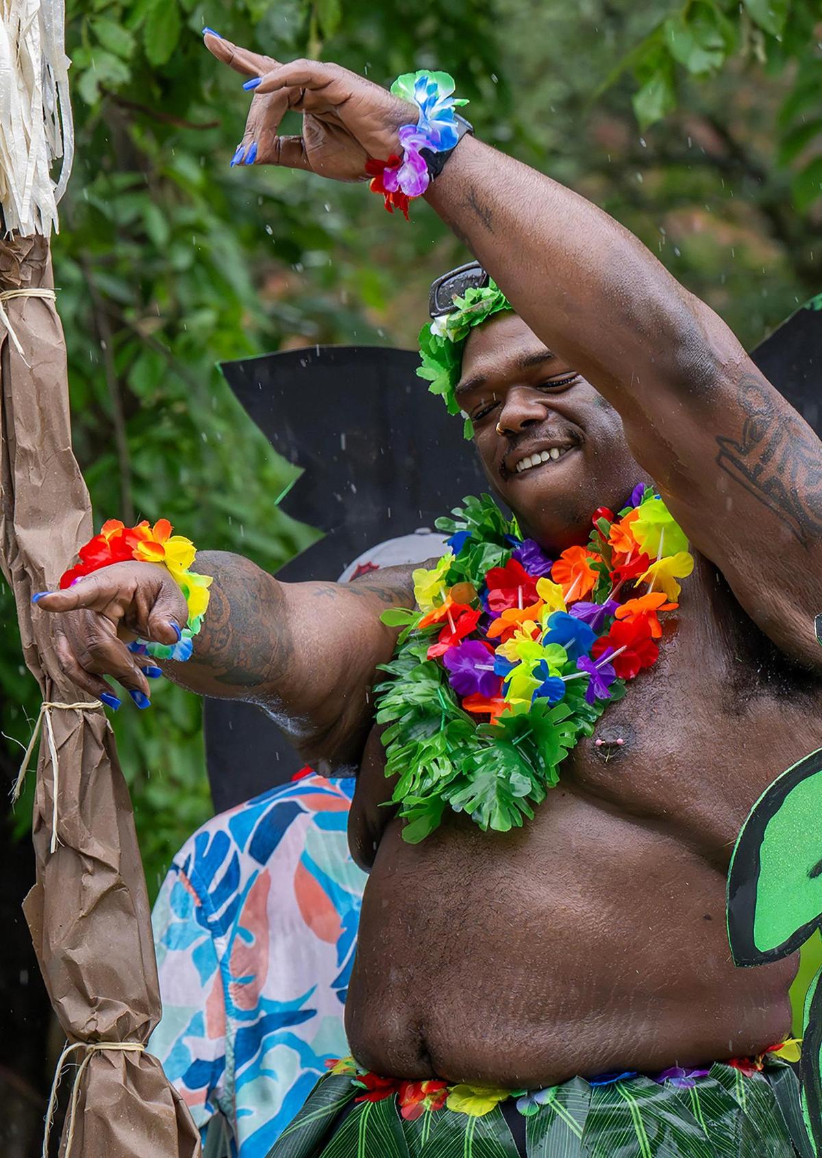 Dressed in grass skirt and lei, a parade participant dances during the KC Pride Fest.