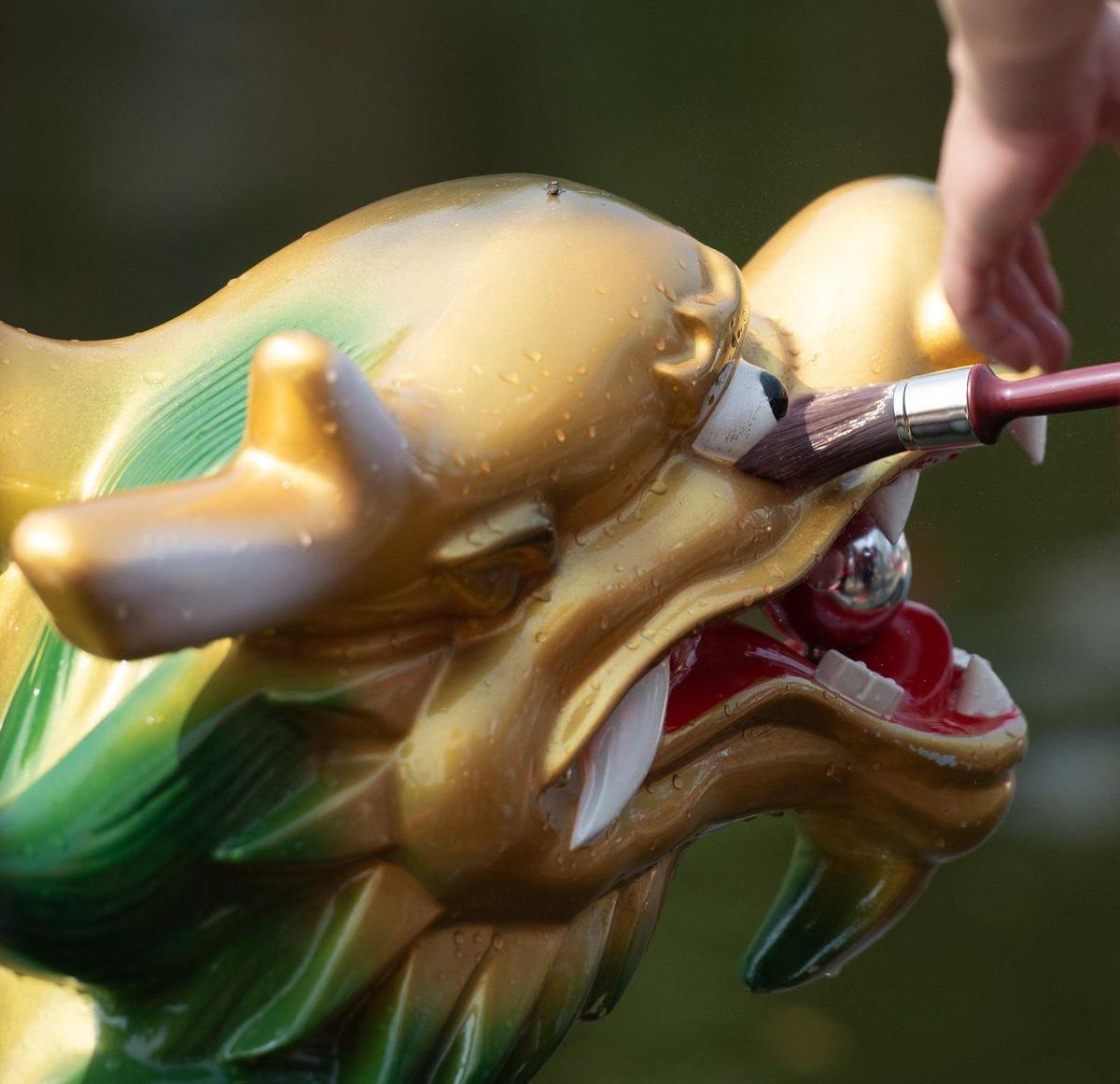 Kansas City Mayor Pro Tem Ryana Parks-Shaw performs the dragon eye opening ceremony by swiping a damp brush over the eye of a dragon boat at the start of 18th annual Kansas City Dragon Boat Festival.