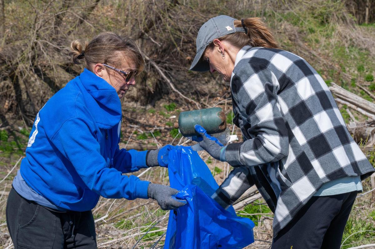 Sisters Lorraine Hills and Lisa LaCombe fill a trash bag with trash from the banks of the Missouri River during an event Saturday held by Missouri River Relief.