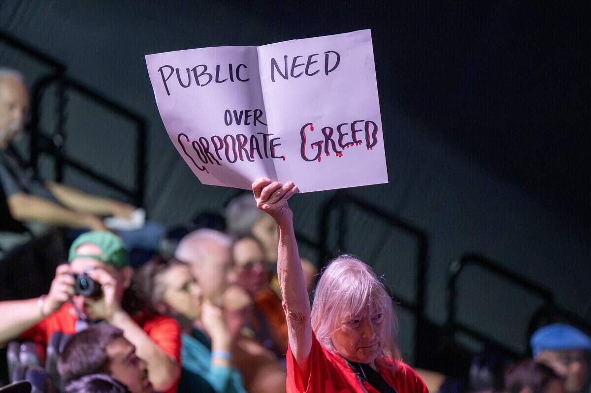 A member of Stand Up KC holds up a sign during a presentation about the proposed rezoning of Crown Center for a new Kansas City Royals ballpark at the Regnier Theatre inside Union Station on Monday, July 27, 2026, in Kansas City.