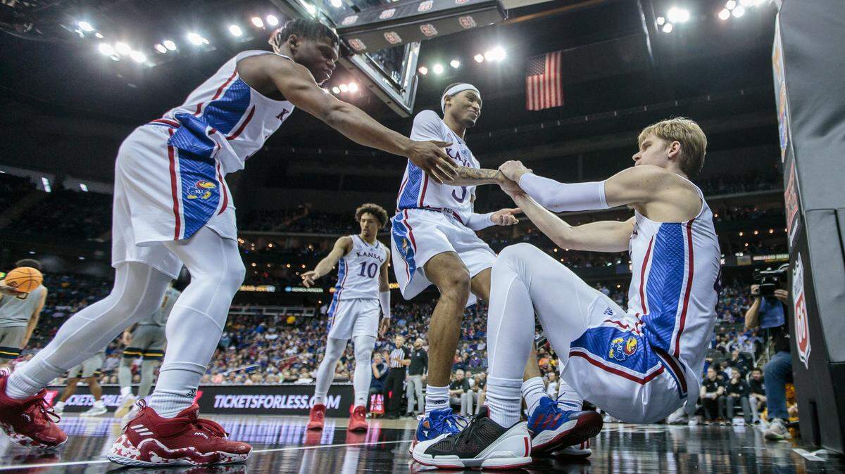 Kansas Jayhawks guard Dajuan Harris Jr. (3) and guard Kevin McCullar Jr. (15) help guard Gradey Dick (4) up after a play during the second half against the West Virginia Mountaineers at T-Mobile Center on March 9, 2023.