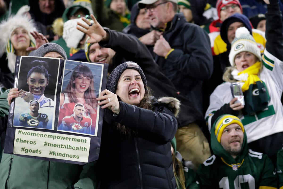 A fan shows off a sign of Simone Biles and Taylor Swift during the game between the Kansas City Chiefs and the Green Bay Packers at Lambeau Field.