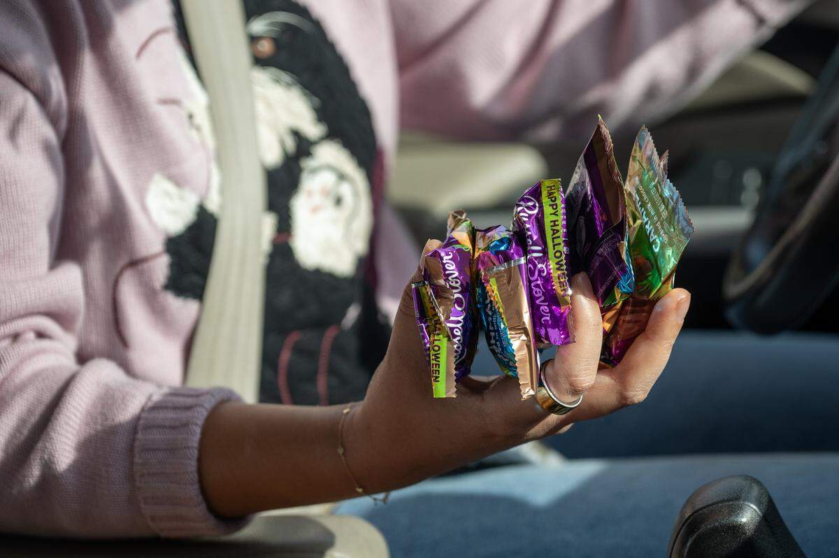 A visitor holds a large amount of candy as they drive away from Russell Stover's headquarters during the company's annual Halloween giveaway on Friday, Oct. 31, 2025, in Kansas City.