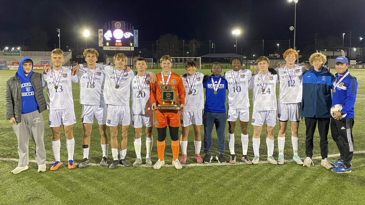 The Rockhurst soccer team gathers to hold the Missouri Class 4 state soccer trophy last Saturday after finishing 24-0-0.