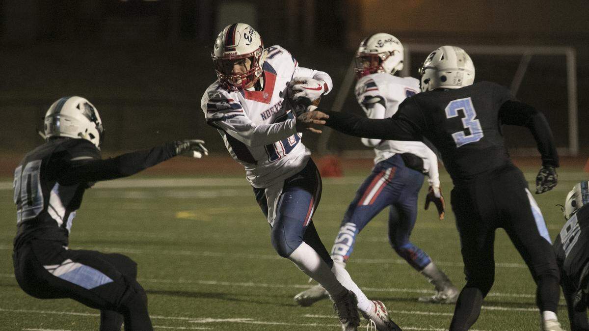 Olathe North quarterback Arland Bruce IV worked to burst up field against the Shawnee Mission East defense in Friday’s game at Shawnee Mission North.