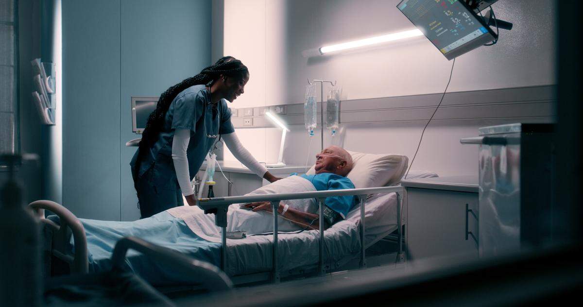 Bed, nurse and senior patient in hospital for help, support and happy with care. People, professional and smile for healthcare at clinic for illness or sickness and recovery with treatment or medical