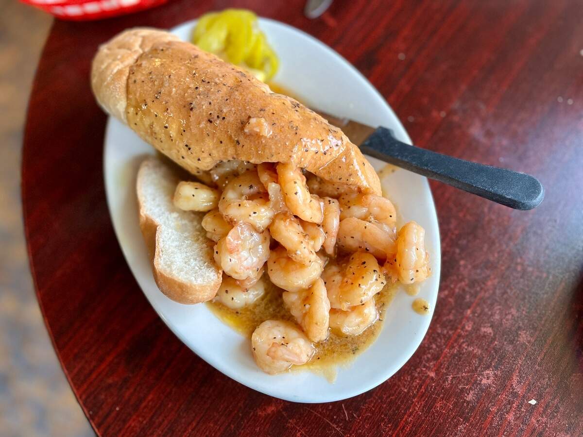 The Barbecue Shrimp Poboy is served on a loaf of hollowed-out New Orleans French bread overflowing with shrimp and sauce. A knife and fork is recommended.