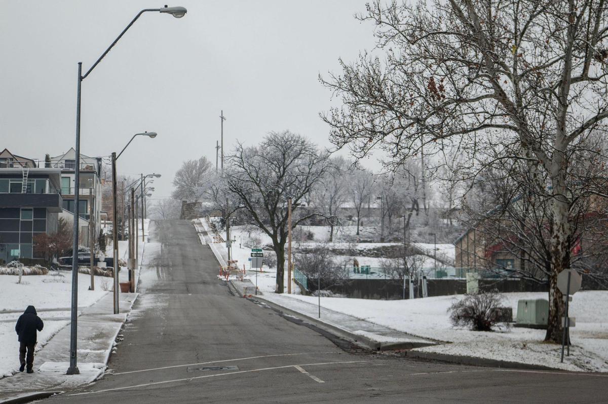 A pedestrian walks near the corners of West 21st Street and West Pennway Street during a light snow fall on Wednesday, Jan. 25, 2023, in Kansas City.