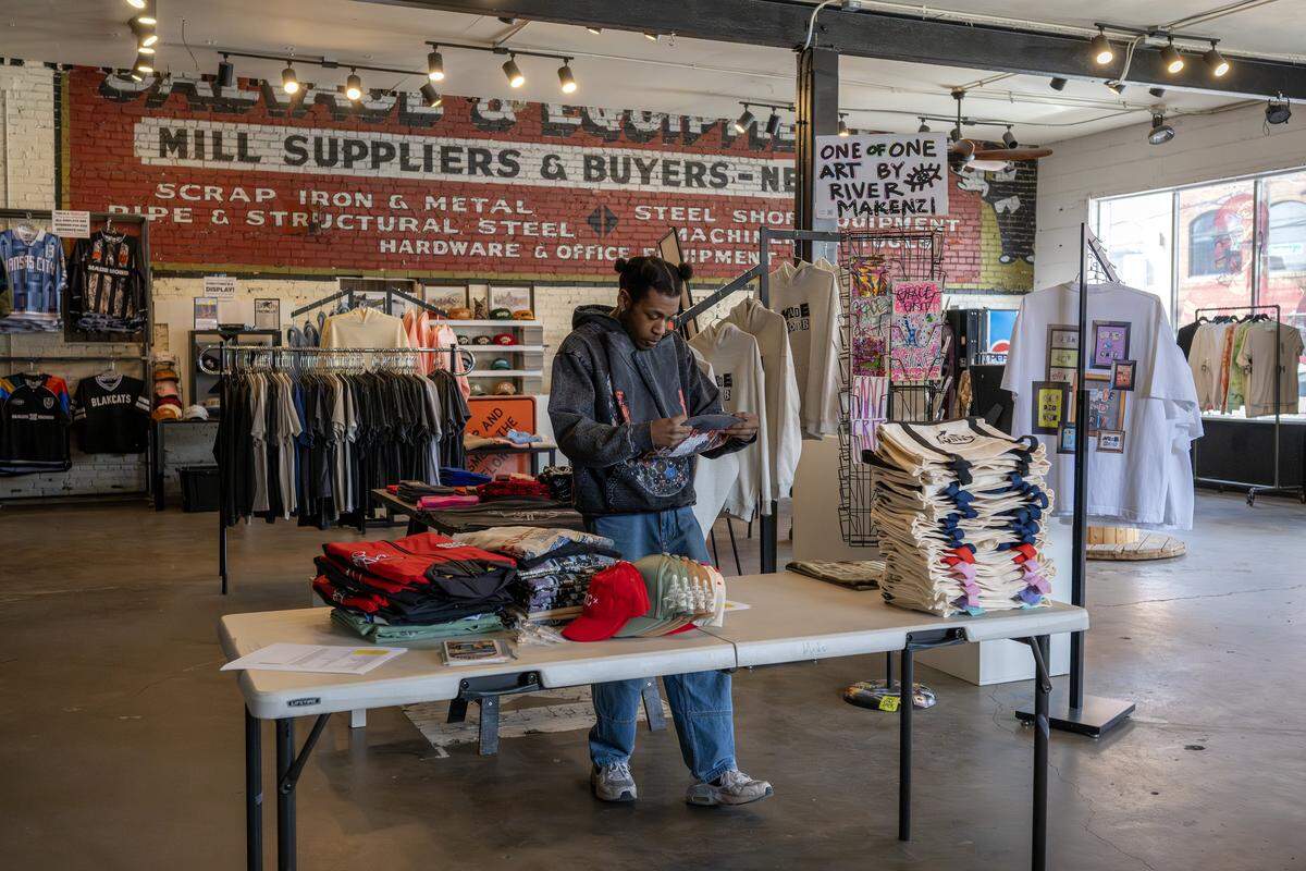Myles Chavis folds a T-shirt near a display table at Made Mobb on Wednesday, March 18, 2026, in Kansas City.