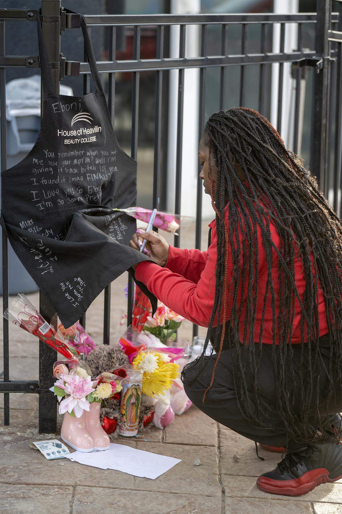 After a memorial balloon release Monday, Feb. 16, 2026, in Kansas City, Dezzie Johnson of Kansas City, signed an apron in memory of her sister-in-law, Eboni Silas, who was fatally shot in a Kansas City nightclub on Sunday. The apron was Silas’ from her time at House of Heavilin Beauty College and it was displayed as part of a memorial outside the club.
