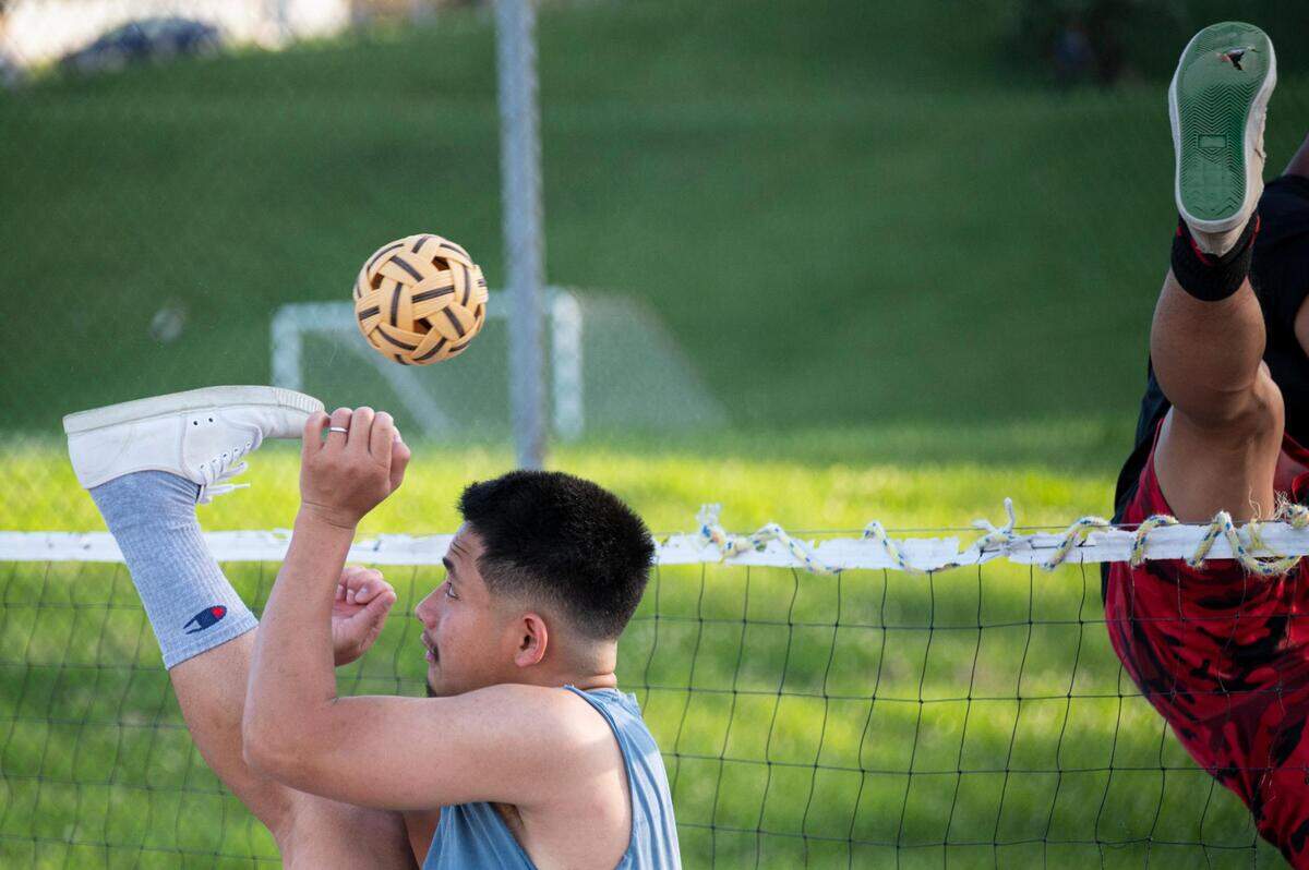 Day Lo kicks the ball as he and his friends play chinlone late in the afternoon at Sheffield Park in Kansas City on June 13, 2022.