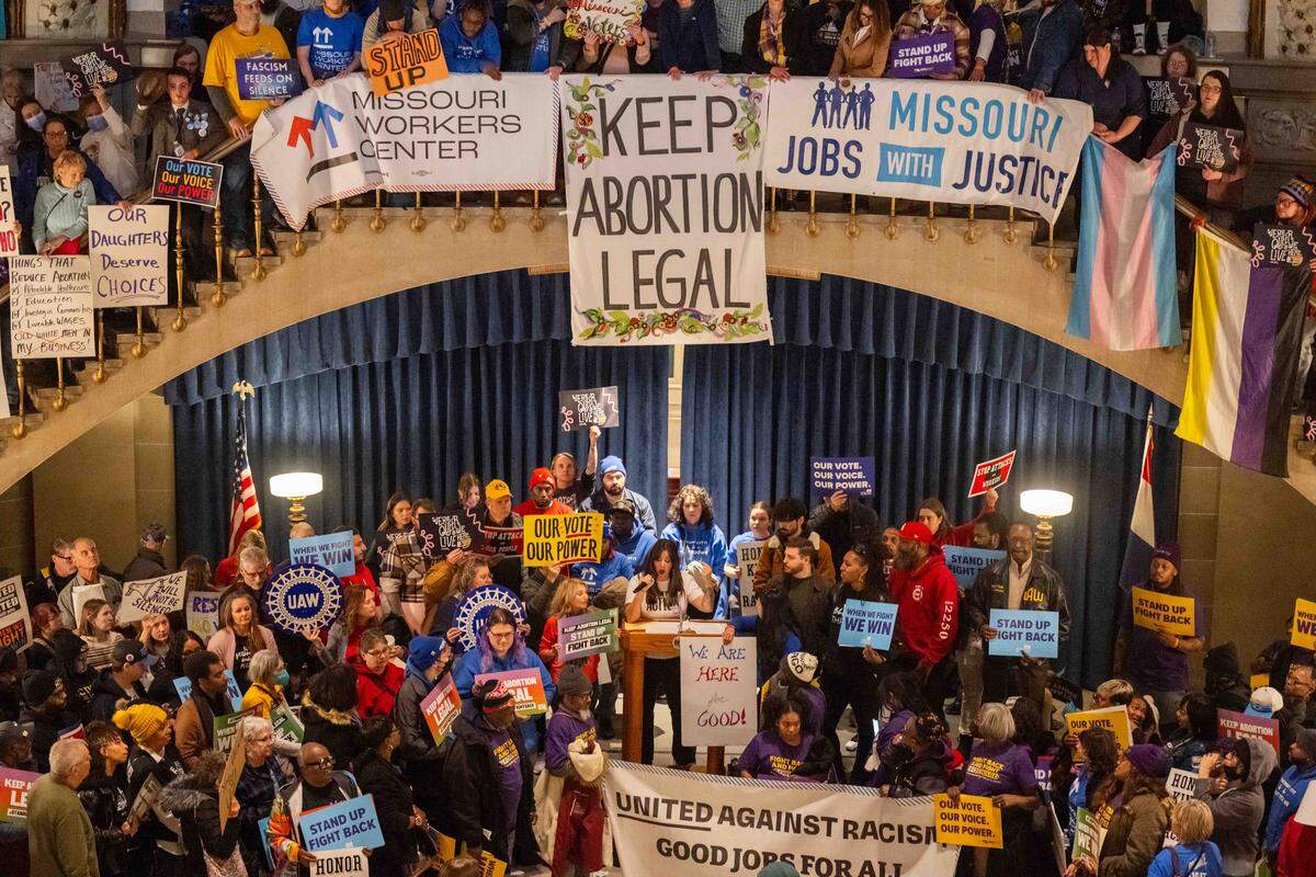 Protesters hold signs as Ashley Jaworski speaks in the Missouri State Capitol rotunda on Wednesday, January 21, 2026 in Jefferson City. Organizations and allies gathered to protest recent Missouri lawmaker's decisions.
