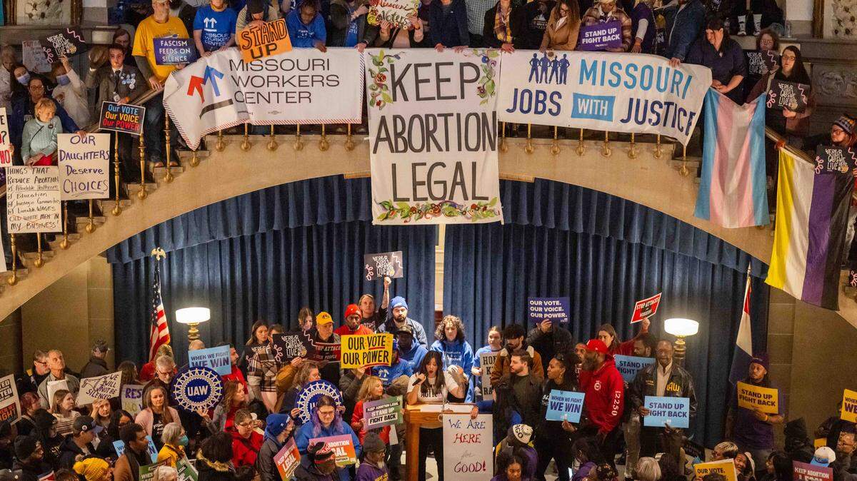 Protesters hold signs as Ashley Jaworski speaks in the Missouri State Capitol rotunda on Wednesday, January 21, 2026 in Jefferson City. Organizations and allies gathered to protest recent Missouri lawmaker's decisions.