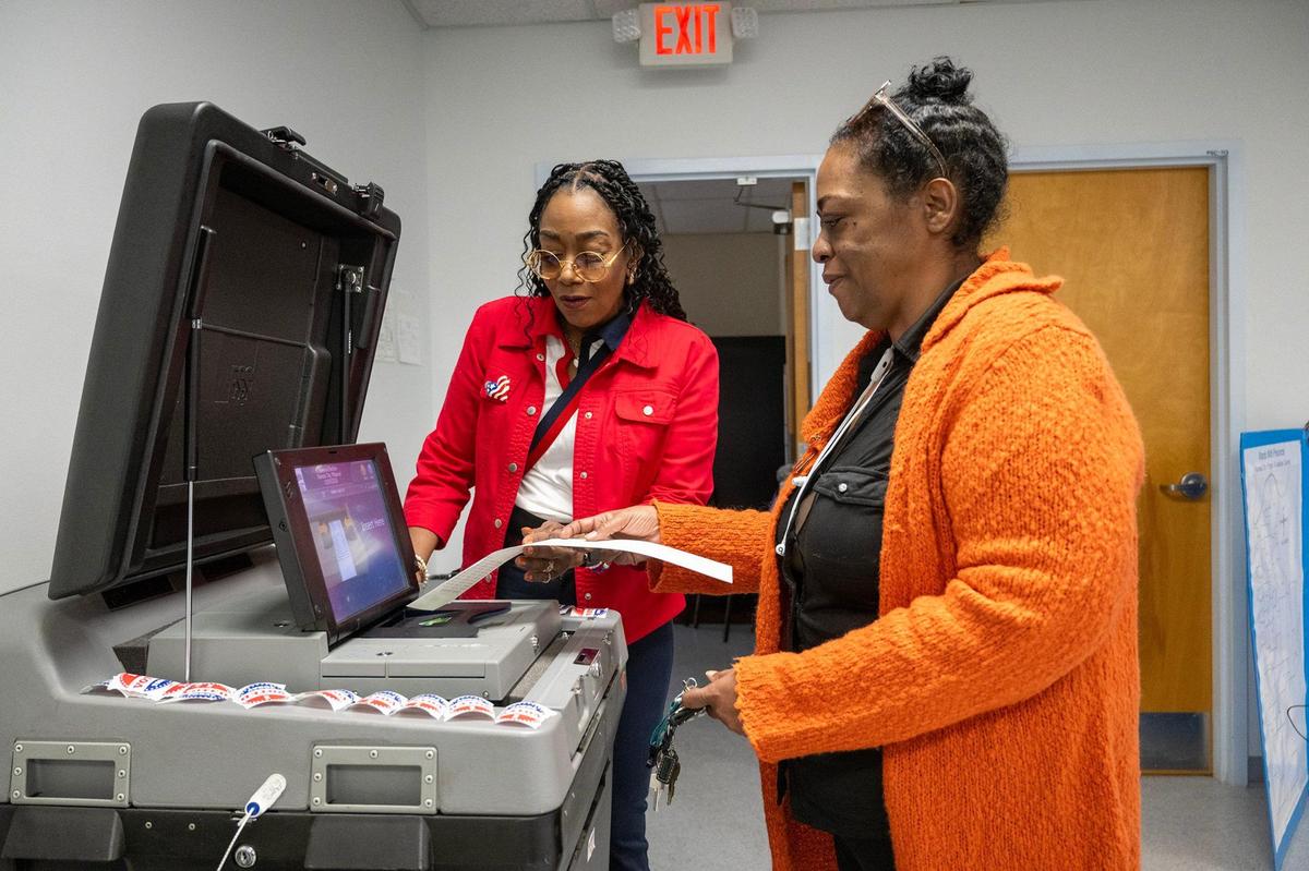 Lauri Ealom, left, part of the Kansas City Board of Election Commissioners, helped Arrion Abernathy of Kansas City insert her ballot into the machine after voting at the Palestine Senior Center on Tuesday in Kansas City. It was the first day of no-excuse absentee voting for Kansas City residents.