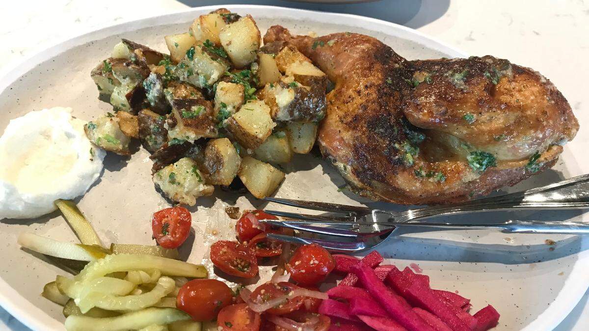 The roast chicken entree at Meddys comes with garlicky potatoes, tomato-onion relish, pickles and pita.