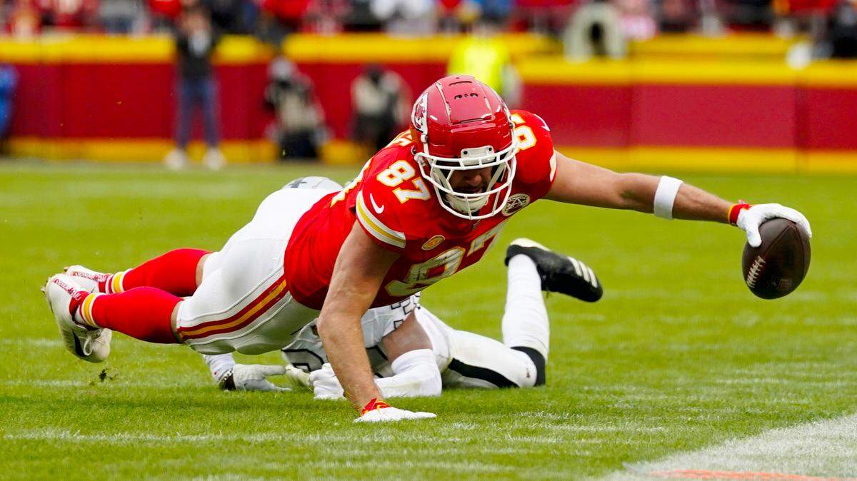 Kansas City Chiefs tight end Travis Kelce (87) dives for the sideline against Las Vegas Raiders cornerback Nate Hobbs (39) during the first half at GEHA Field at Arrowhead Stadium.