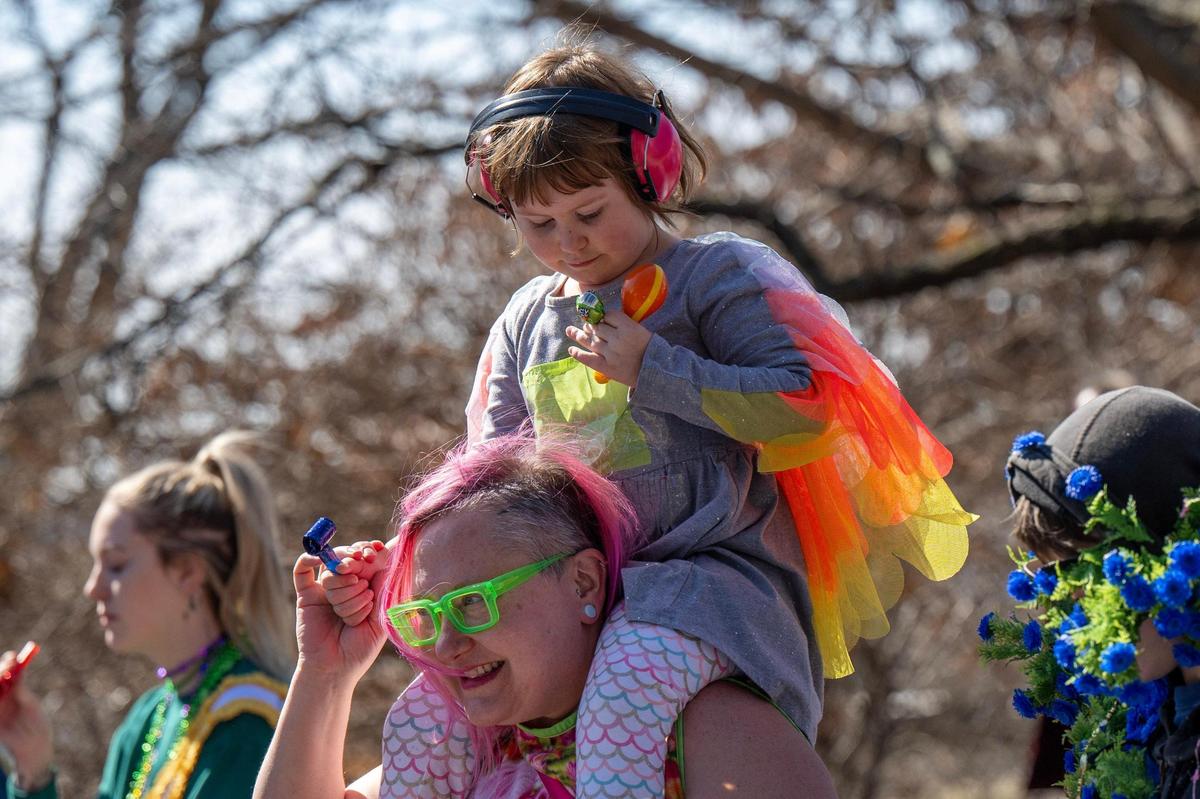 Tess Allen holds her five-year-old daughter, Electra, on her shoulders as they participate in the Krewe de Prank parade on Sunday, March 2, 2025, in Kansas City.