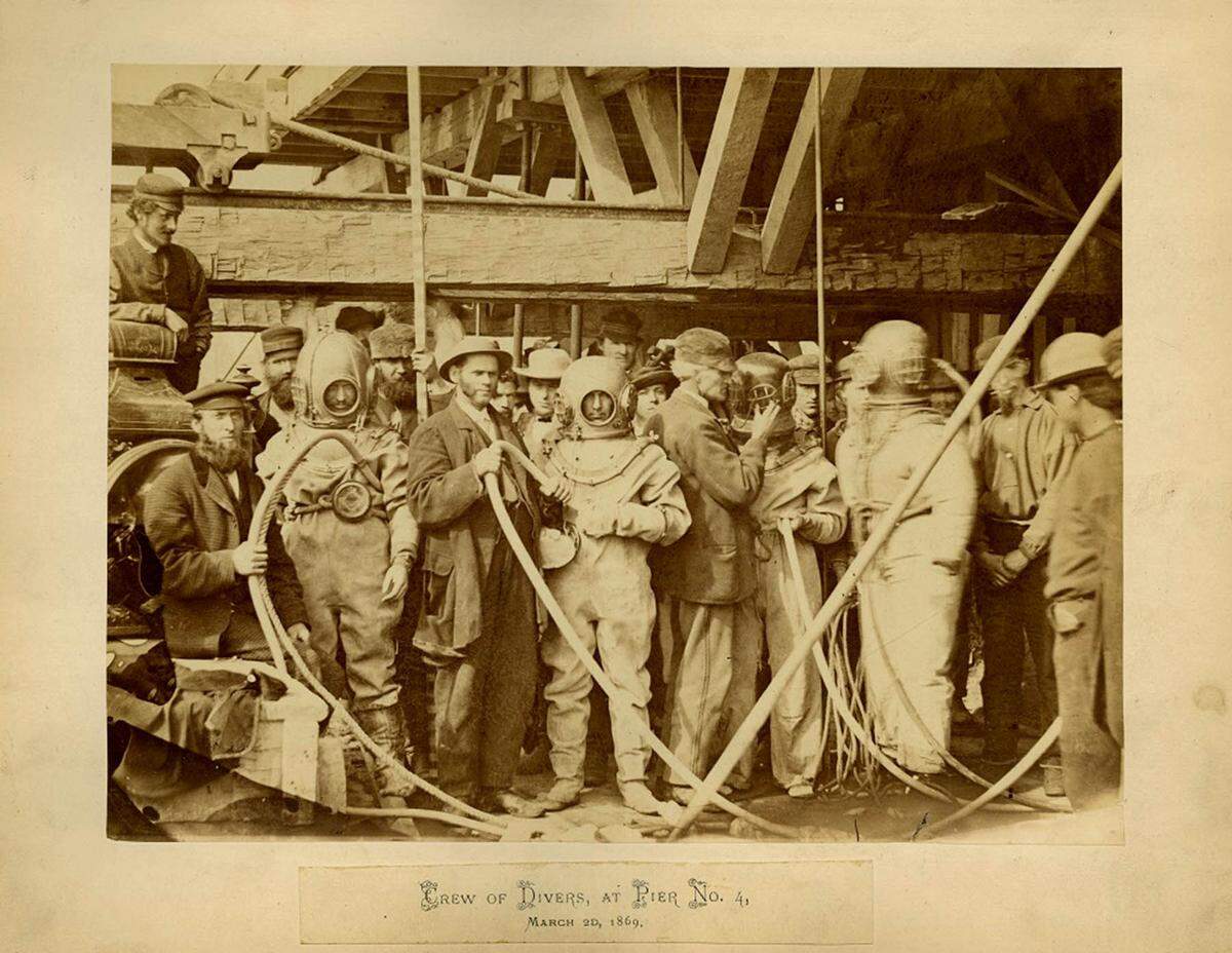 A crew of divers at Pier No. 4 on March 20, 1869 pose for a photo during the construction of the Hannibal Bridge. The divers were hired to work below the surface of the Missouri River to help with the construction project.
