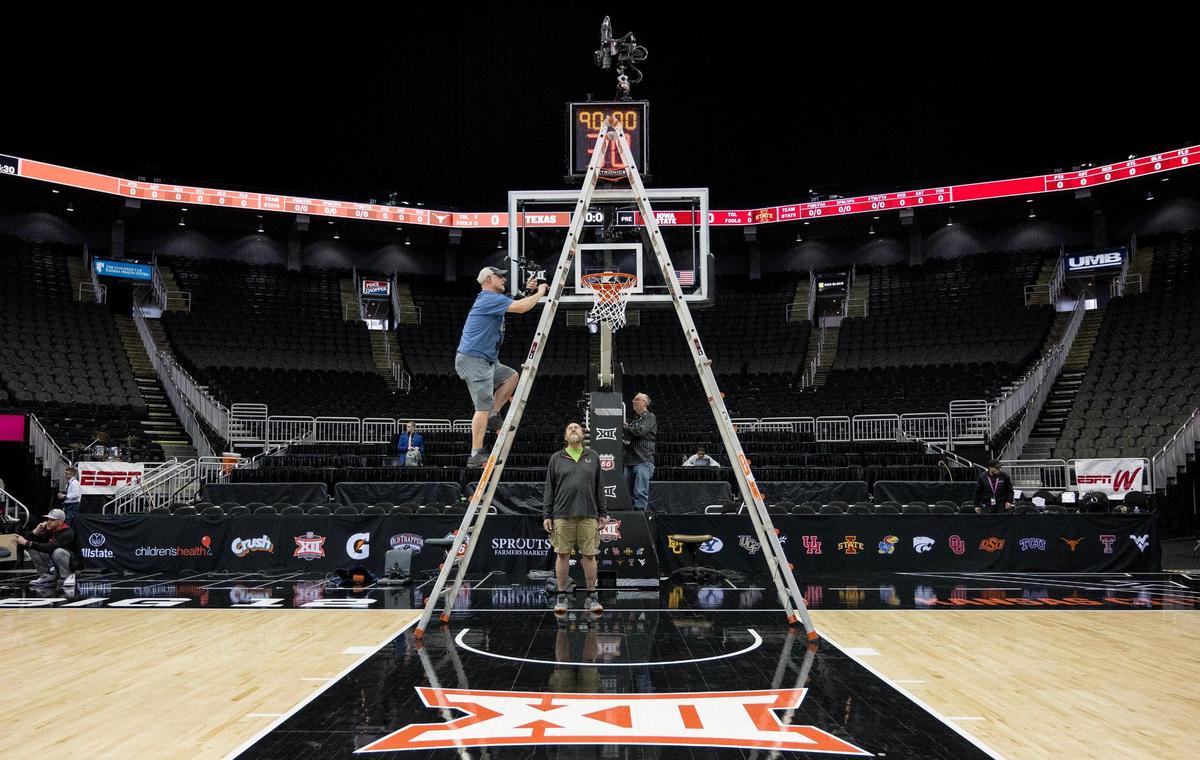 Rick Beattie, a robotic camera operator, climbs a ladder Tuesday to adjust a camera that sits above one of the baskets during the Big 12 basketball tournament at T-Mobile Center.