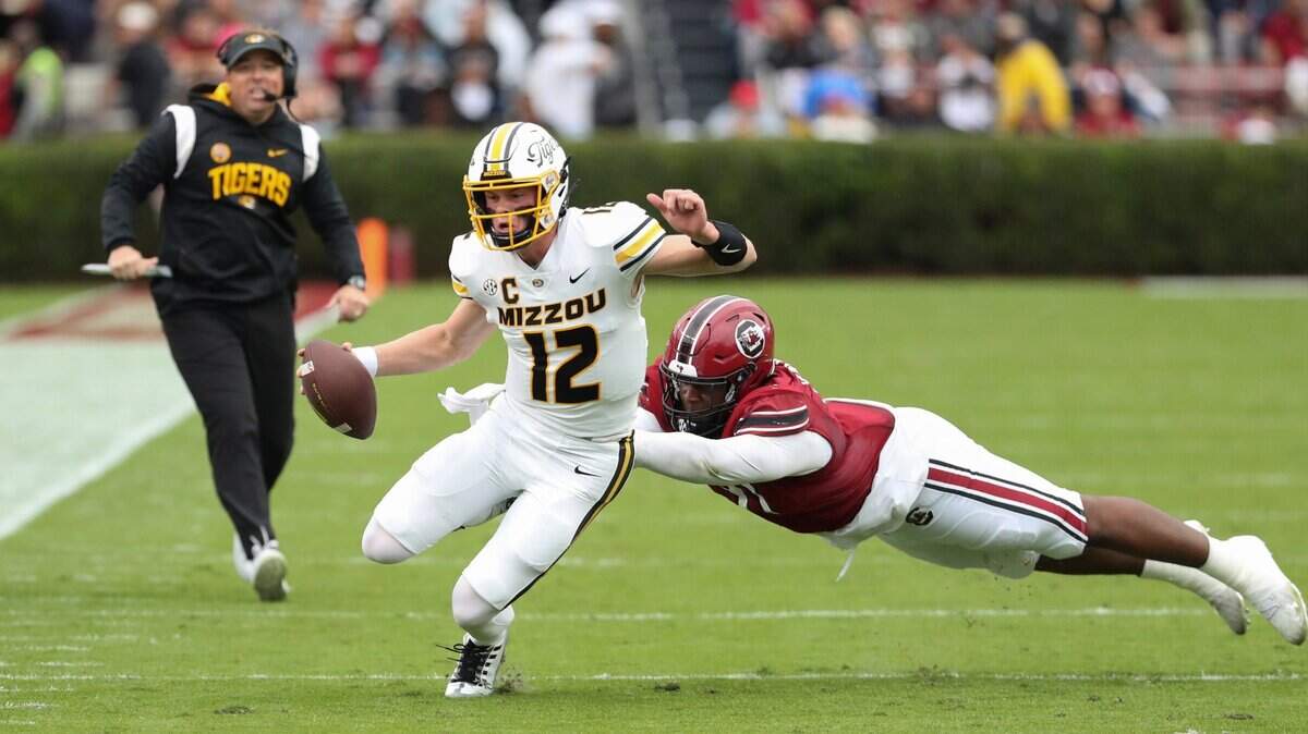 Missouri quarterback Brady Cook works to elude South Carolina defensive lineman Tonka Hemingway during Saturday’s game in Columbia, S.C. (Oct. 29, 2022)
