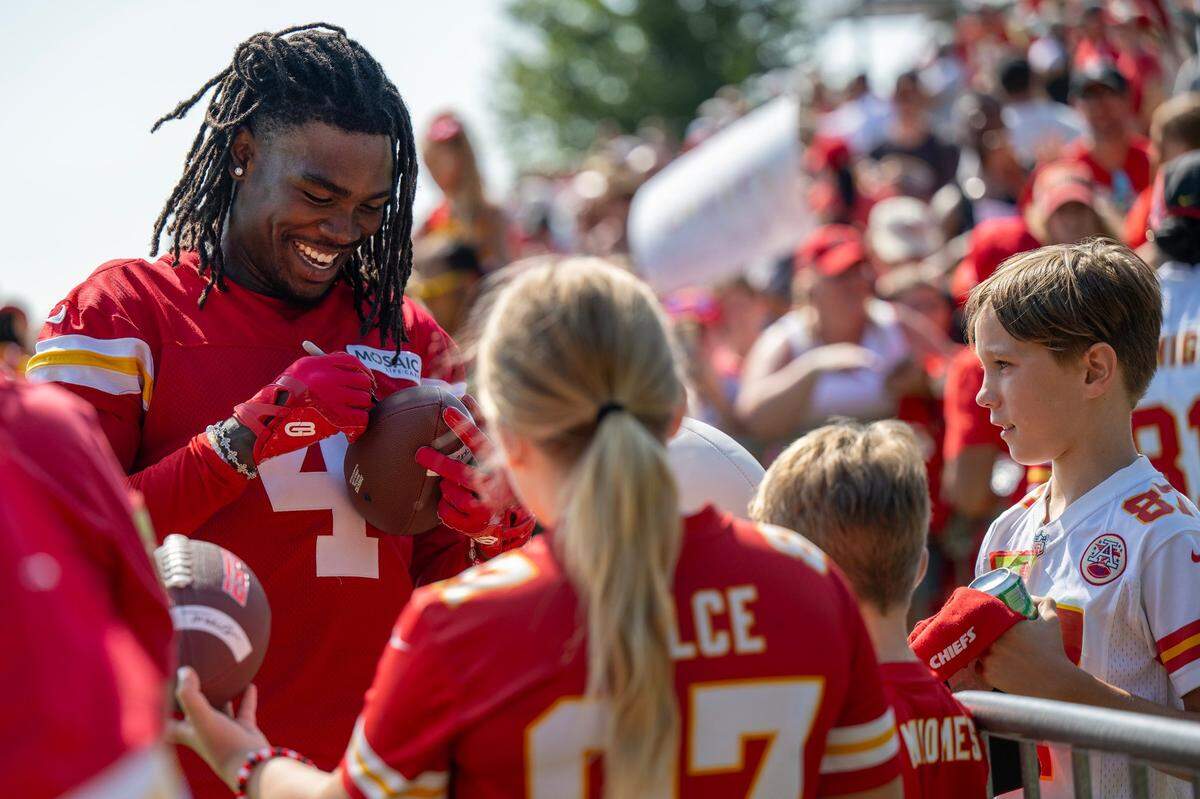 Kansas City Chiefs wide receiver Rashee Rice smiles as he signs autographs for fans after a training camp practice.