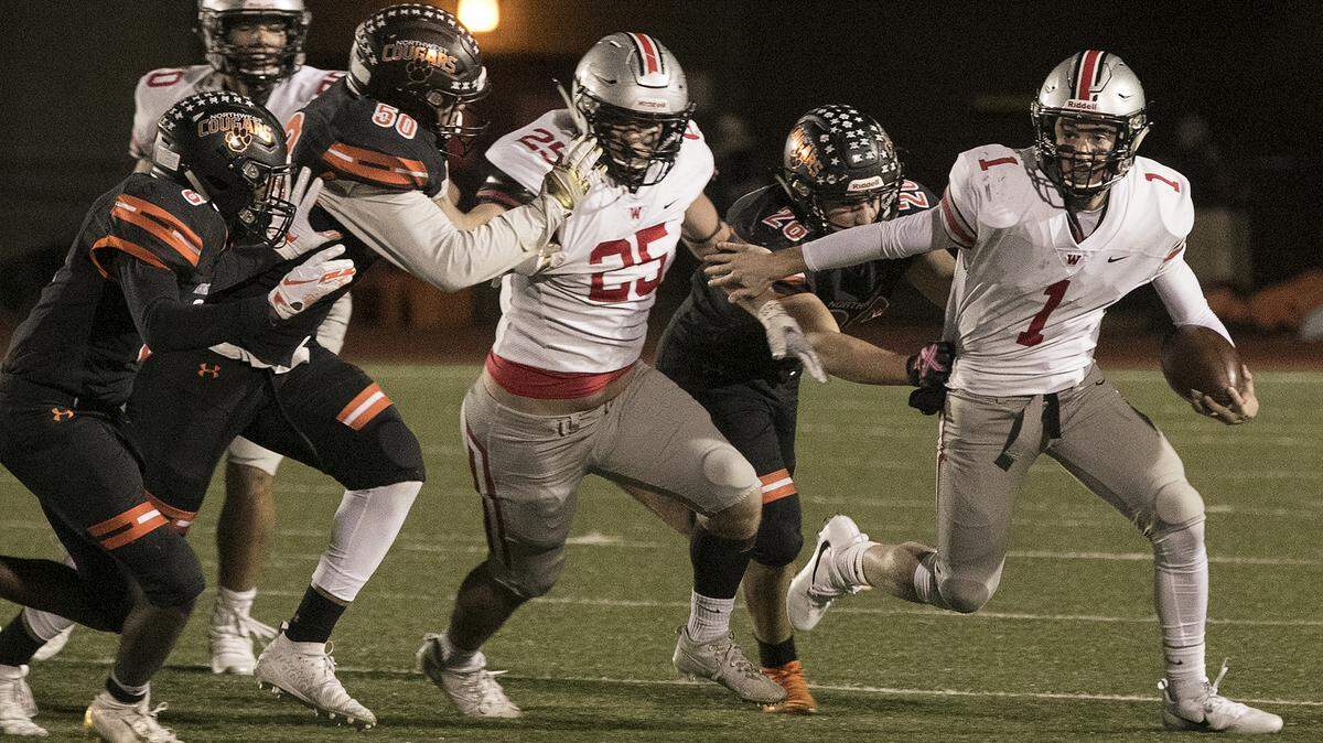 Greg Riddle (right), the quarterback for Blue Valley West, tried to work his way around the Shawnee Mission Northwest defense during Friday night’s game at Shawnee Mission North Stadium.