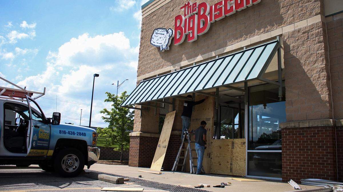 Workers cover the shattered vestibule window of The Big Biscuit in Overland Park with plywood after a car drove through the storefront Wednesday morning. No one was hurt in the crash.