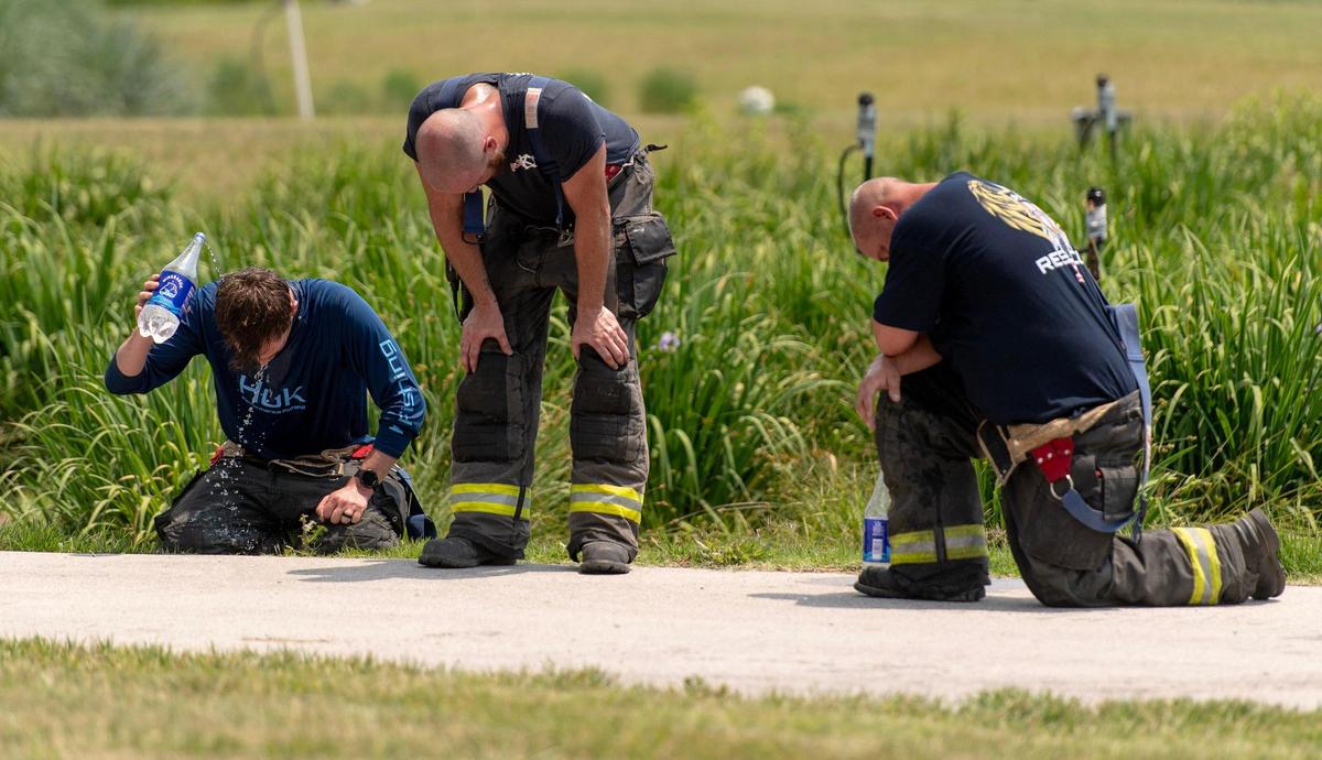 Firefighters cool off after battling a blaze at Pioneer Pallet in the 3500 block of Nicholson Ave. on Thursday, June 15, 2023, in Kansas City.