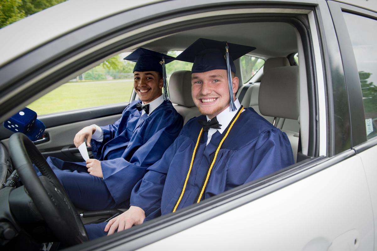 Graduating seniors Derrick Cannon, left, and Blake Avery Bland were all smiles during a drive-up photo session on Friday at Oak Park High School in the North Kansas City school district. The coronavirus has forced the cancellation of in-person graduation, so the school is planning a virtual ceremony for the 356 graduates on May 28, 2020.