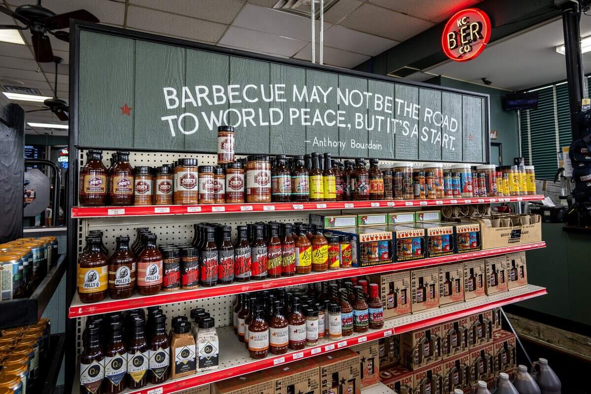 Barbecue sauces and seasonings line a shelf beneath a sign reading “Barbecue may not be the road to world peace, but it's a start,” a quote by Anthony Bourdain, at Joe's KC BBQ on Thursday, April 30, 2026, in Kansas City, Kansas.