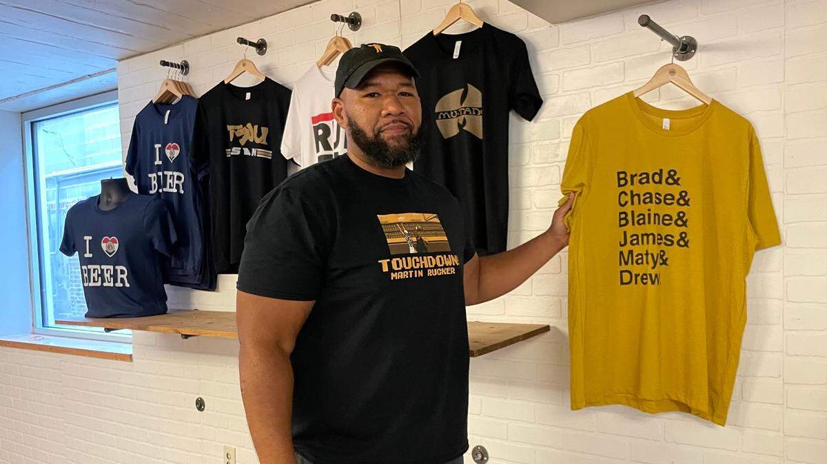 Miki Merritt shows off his first T-shirt design at his 573 Tees storefront in Columbia, Missouri.