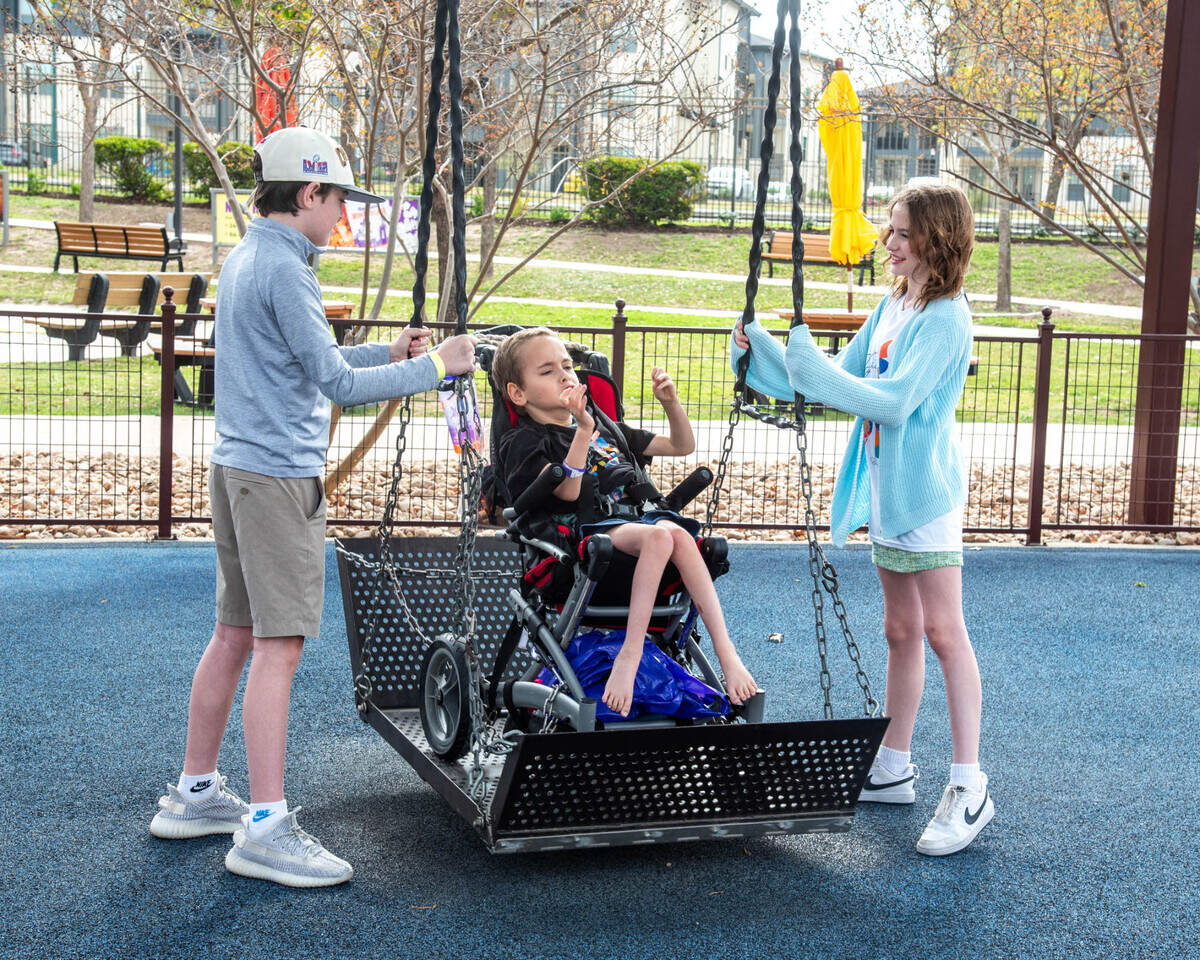 Lamar Hunt Jr.’s grandchildren, James Arkell, 16, Michael Arkell, 10, and Claire Arkell, 12, play on the swings in the park area of Morgan’s Wonderland in San Antonio, Texas.