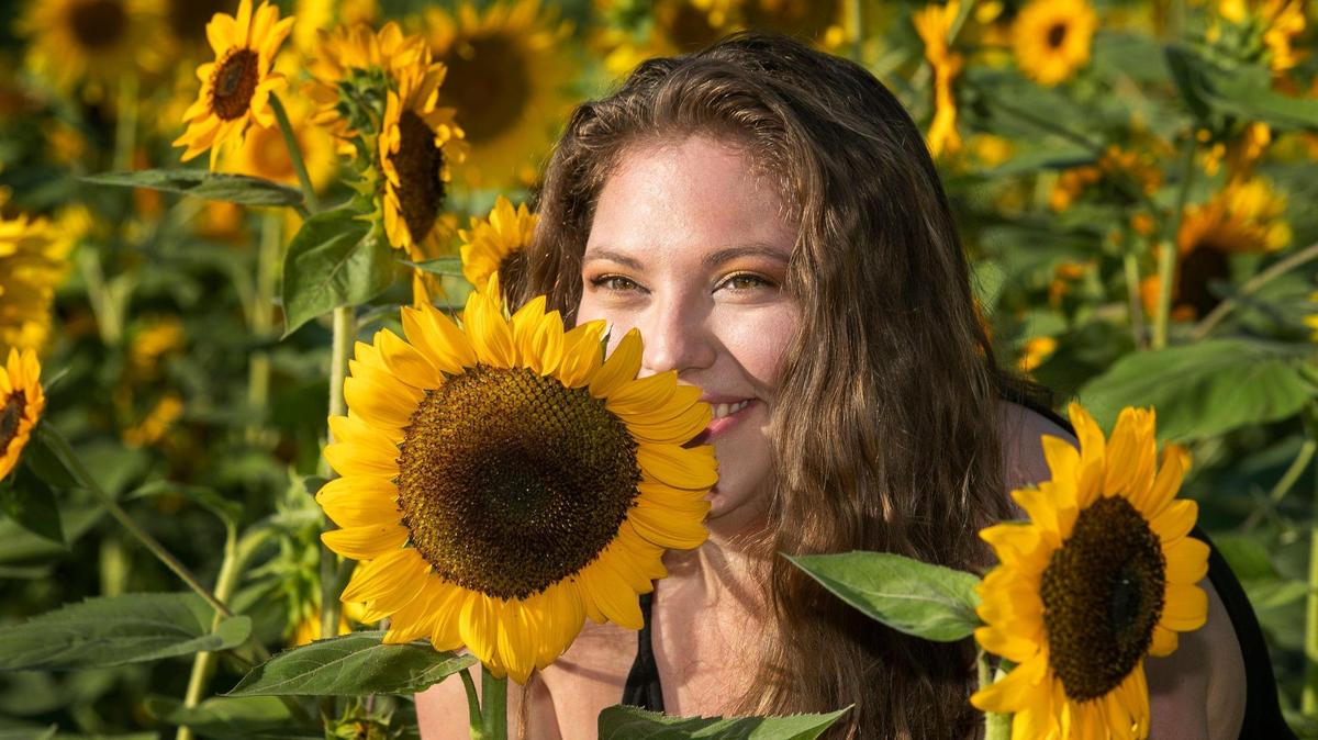 Ashley Johnson of Kansas City, posed for her mom at the KC Sunflower Fest at the KC Pumpkin Patch in Olathe, Friday, August 12, 2022.