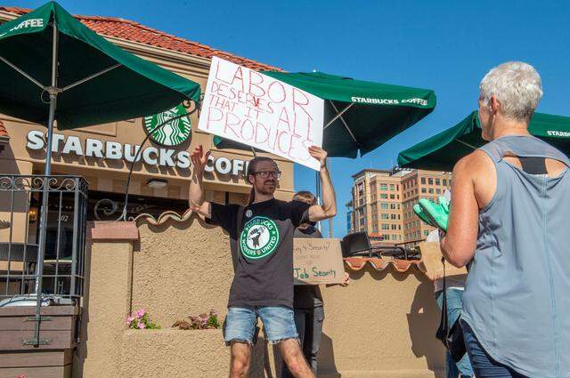 While Starbucks employee Josh Crowell picketed outside the Starbucks Country Club Plaza location Tuesday, a customer stopped to ask for details about why the location had closed. Workers said the company told them the location was being shuttered because of safety and security concerns.