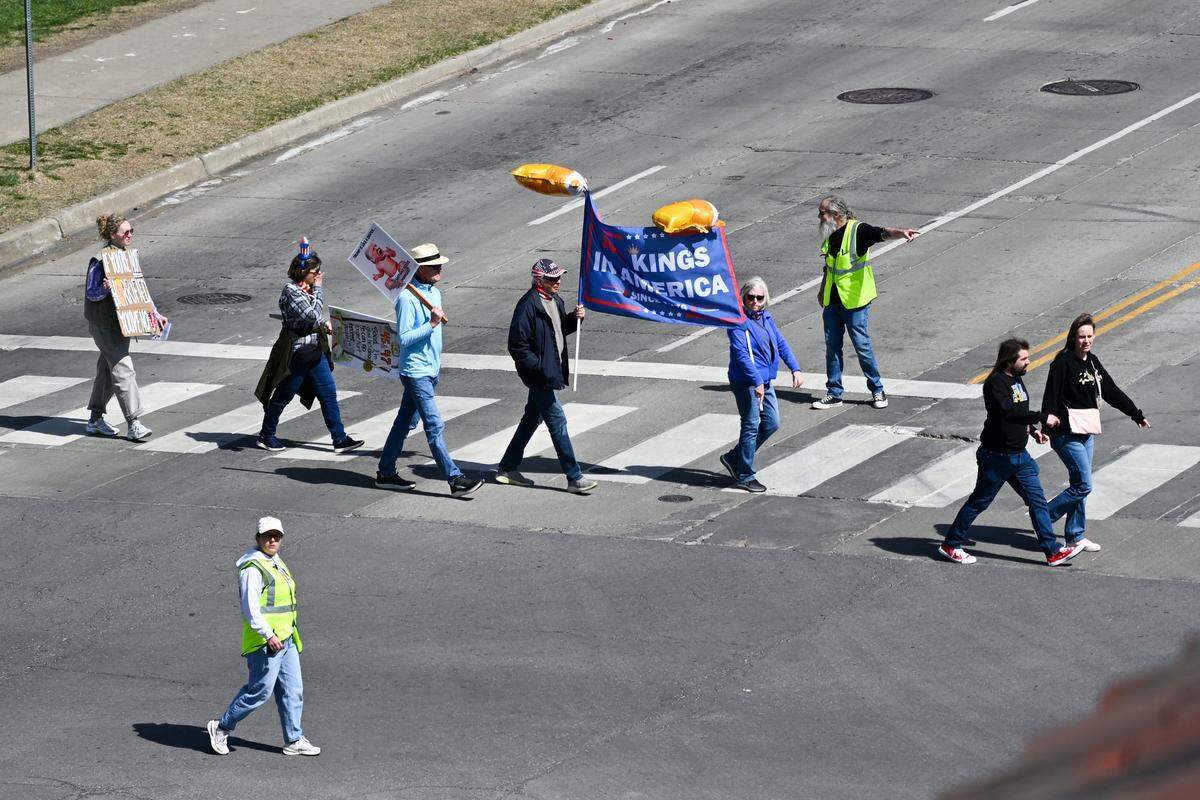 Protesters cross a sidewalk near the Country Club Plaza on Saturday, March 28, 2026, during a No Kings protest against the Trump administration in Kansas City.