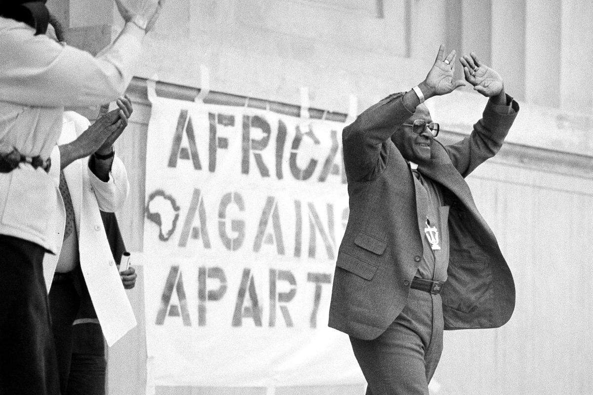 Desmond Tutu greets a crowd of 10,000 people with his hands held high during a rally at the Greek Theater on the University of California at Berkeley, Calif., campus, May 14, 1985. Tutu praised the students for their opposition to apartheid in South Africa. (AP Photo/Eric Risberg, File)