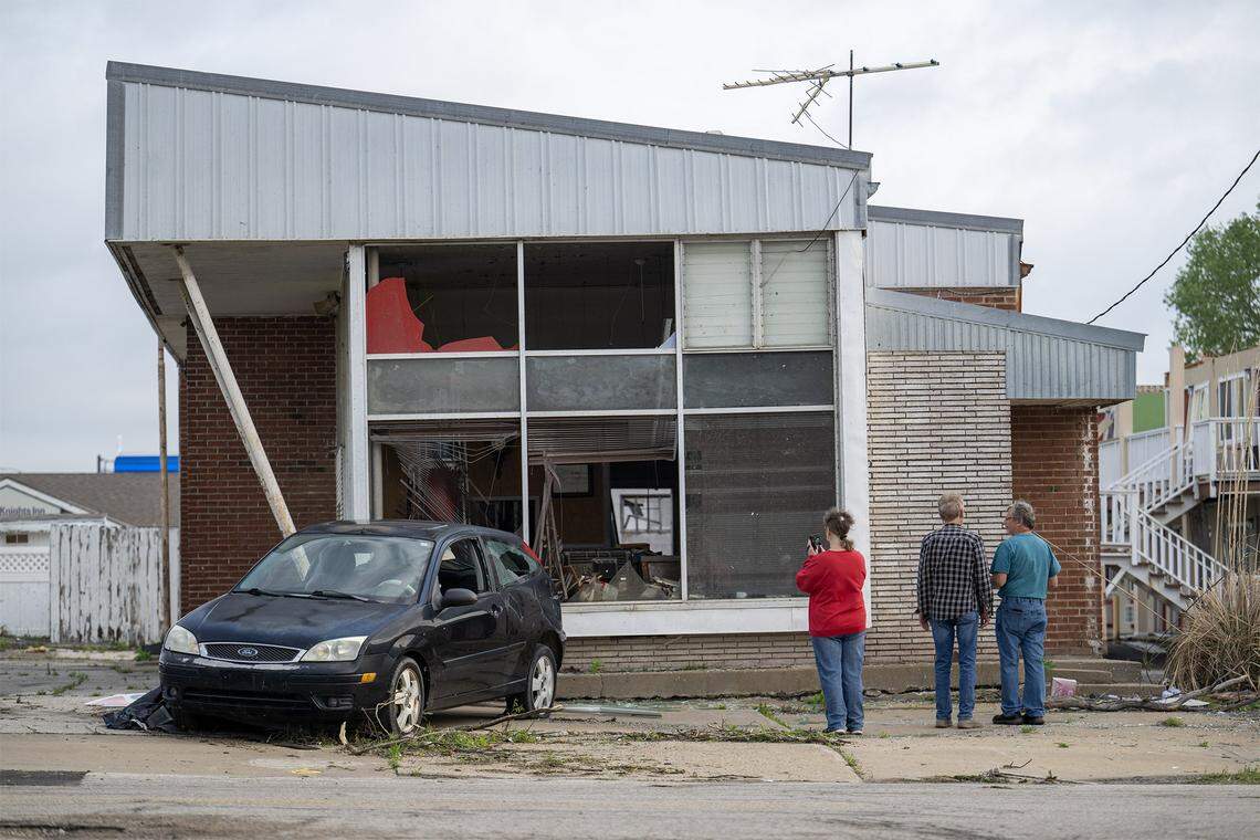Randy McCurdy, right, owner of McCurdy's Auto Sales & Auto Service, and others, looked over damage to his business on Tuesday, April 14, 2026, in Ottawa, Kansas, after a tornado moved through the town Monday night.