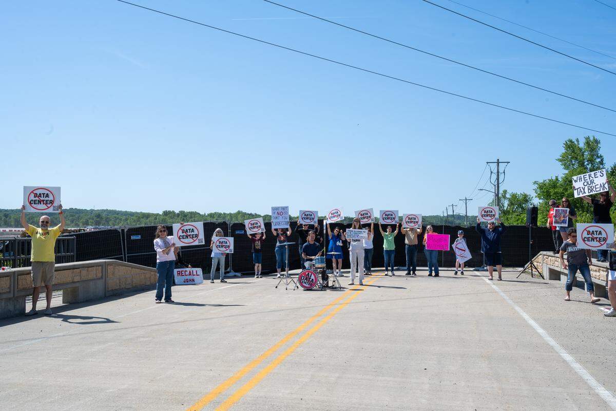 A group of protesters on Bly Road hold signs near the construction site for Nebius, a future AI data center being built in Independence, on Tuesday, May 12, 2026.