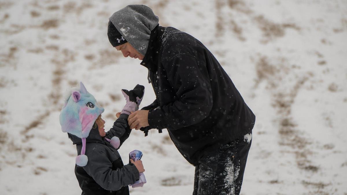 Brent Crawford helped his daughter, Charlotte, 4, with her gloves as the pair went sledding at Meadowbrook Park in Prairie Village on Wednesday. The pair are from Merriam.