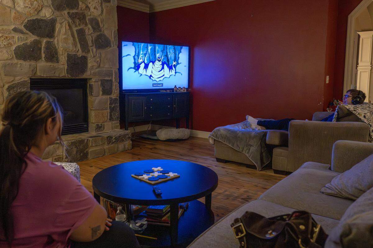 Harrison Long watches Scooby-Doo with his assistant Yasmin Noyola in the living room of his home on Tuesday, Feb. 10, 2026, in Parkville.