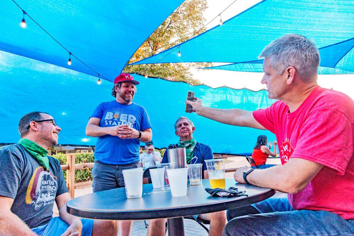 Bier Station owner John Couture, standing, chatted in the expanded outdoor dining area Thursday with friends from the neighborhood, including Mike Young, from left, Aaron Browning and Tim Ahlenius. 