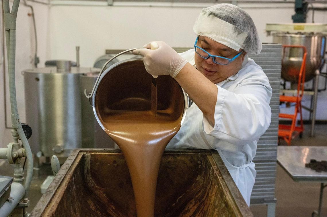 Bob Khotbounheuang pours warm chocolate into a vat during a production run at the Sifers’ Valomilk plant.