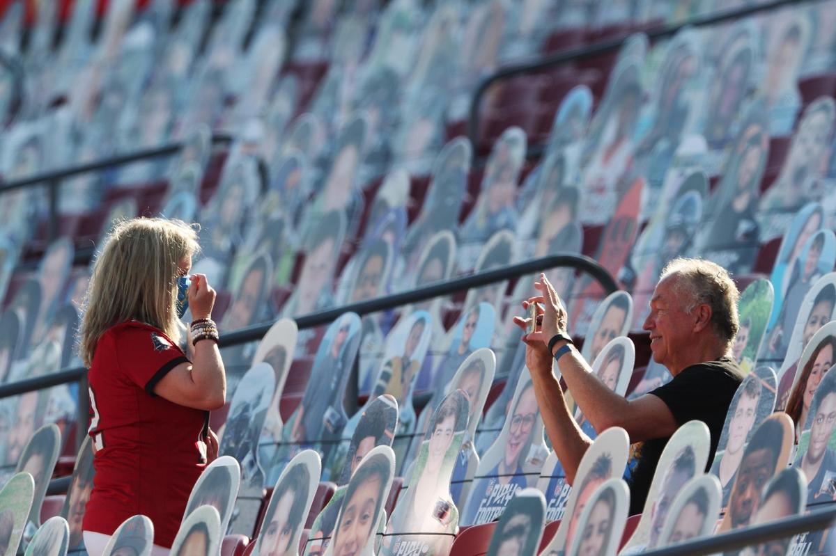Real life fans take photos of themselves among the cutout fans in the stands Sunday, February 7, 2021, before the start of Super Bowl LV at Raymond James Stadium in Tampa, Florida.