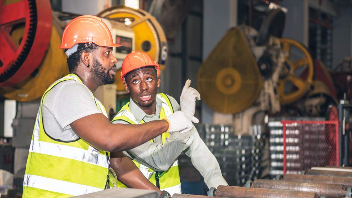 Two male African American workers talking, consulting and discussing, in teamwork in an industrial factory, to engineering and industry concept.