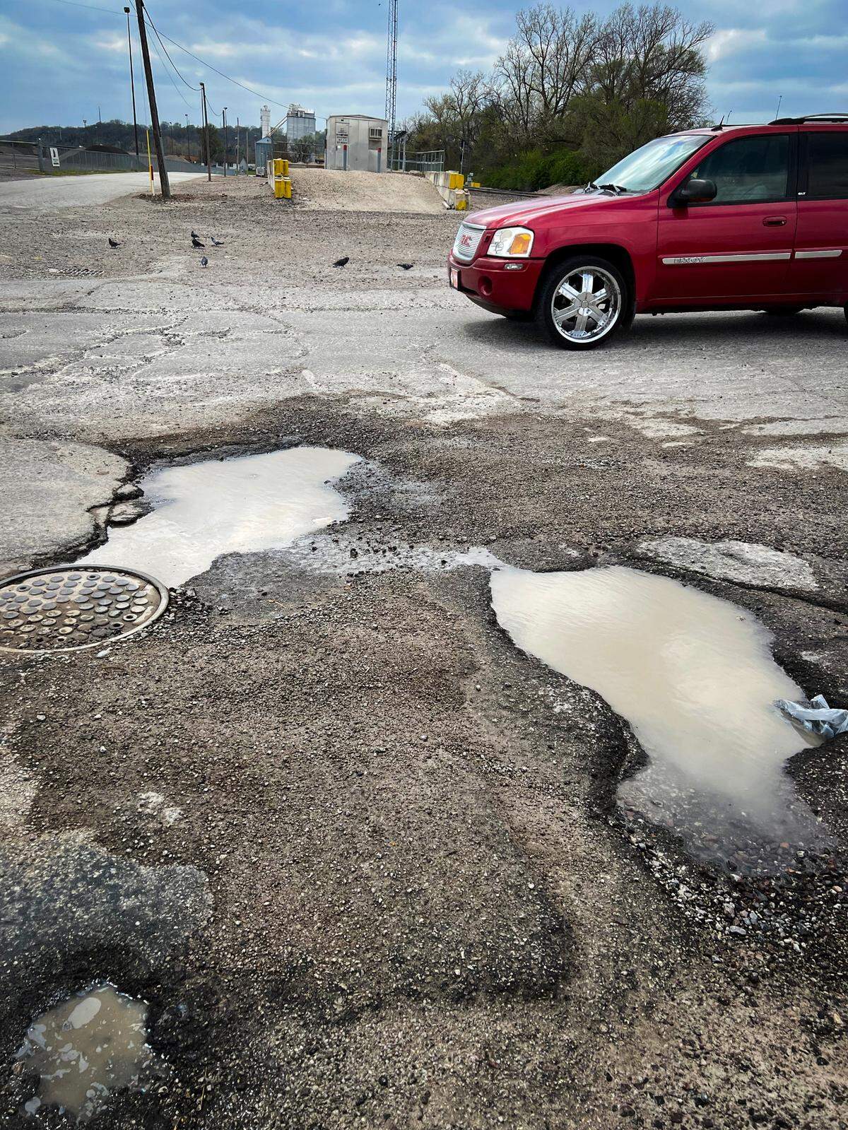 Large potholes filled with water from a recent storm dot the roadway along Genessee Street just off of Southwest Boulevard in Kansas City. The road is a busy thoroughfare to the on ramps for Interstate 35.