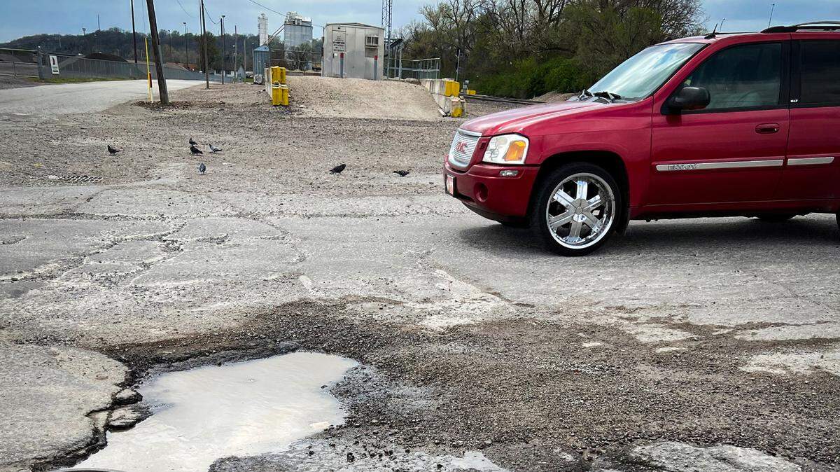 Large potholes filled with water from a recent storm dot the roadway along Genessee Street just off of Southwest Boulevard in Kansas City. The road is a busy thoroughfare to the on ramps for Interstate 35.
